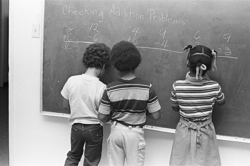 Three Students Working at Chalkboard